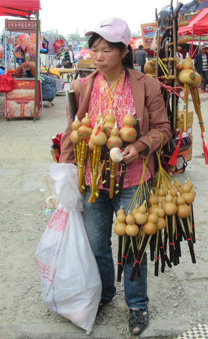 Mujer vendedora de hulusi en un mercado callejero de Dali, en Yunnan, China. Foto: David Stanley. CC BY 2.0. Wikimedia.