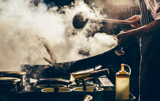 Gastronomia china: un cocinero frie verduras en un wok. Foto: 123RF.