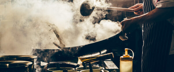Gastronomia china: un cocinero frie verduras en un wok. Foto: 123RF.