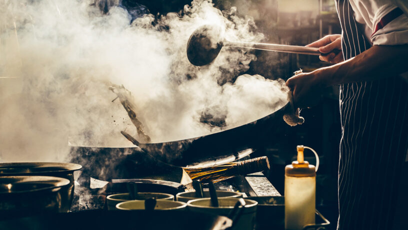 Gastronomia china: un cocinero frie verduras en un wok. Foto: 123RF.