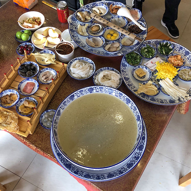 Los «Fideos de arroz cruzando el puente» se sirven rodeados de una gran cantidad de elementos, incluso frutas y postres. Foto: N509FZ, CC BY-SA 4.0, Wikipedia para «Crossing the bridge Noodles.